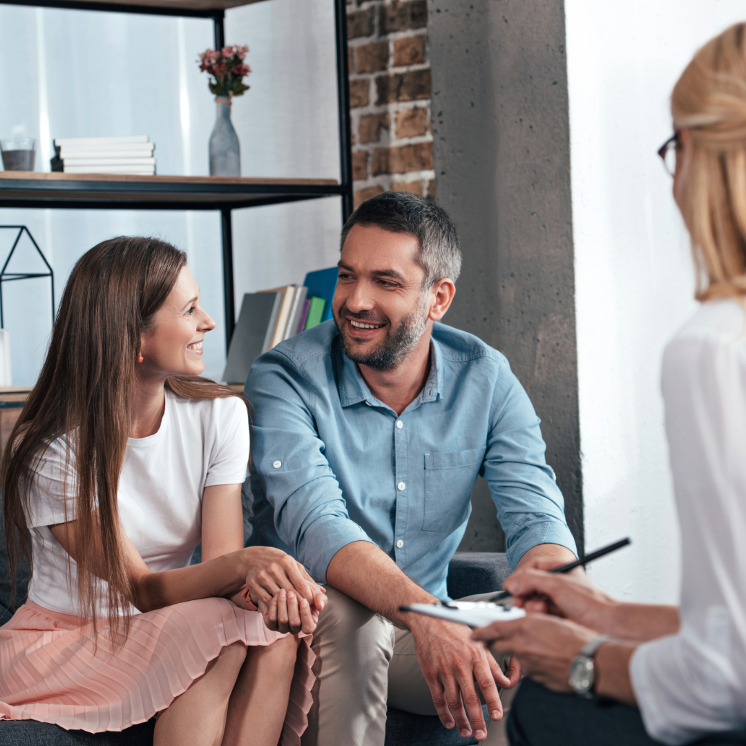 Happy couple in therapy together enjoying the moment as they share their history with the therapist.